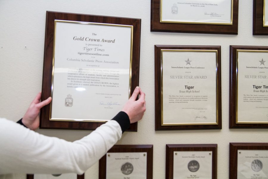 Newspaper adviser Rebbecca Potter hangs the Gold Crown award on the wall.