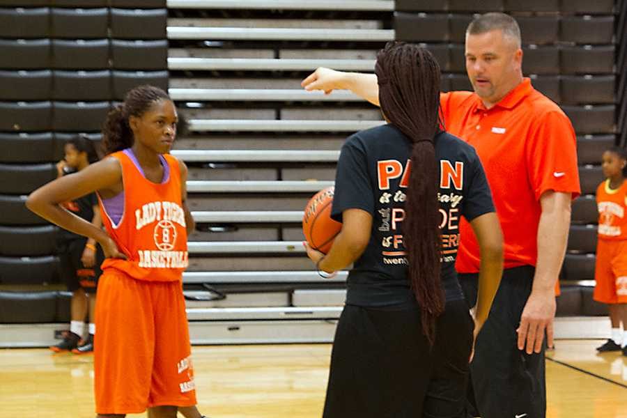 Coach Robert Cochran shows members of the girls basketball team how to run a play.