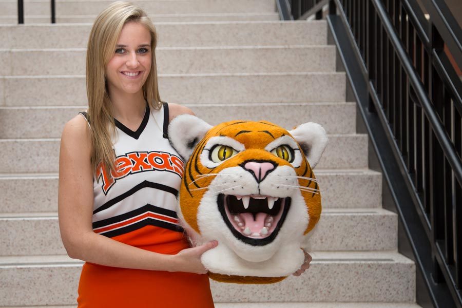 Senior mascot Chandler Thomas poses with mascot costume, showing off her double life