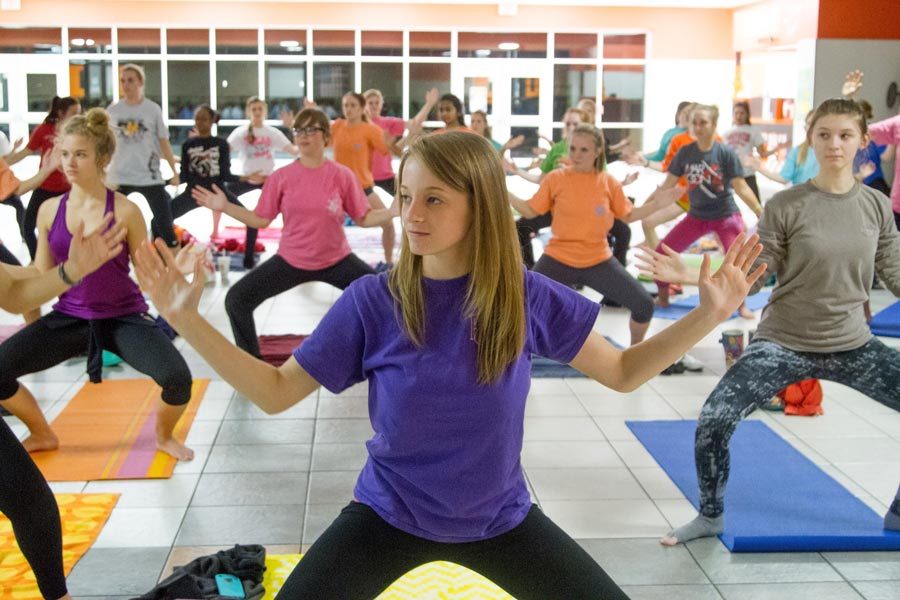 Senior Megan Haselow hits crouching asana with fellow Rosebuds members in Cafeteria