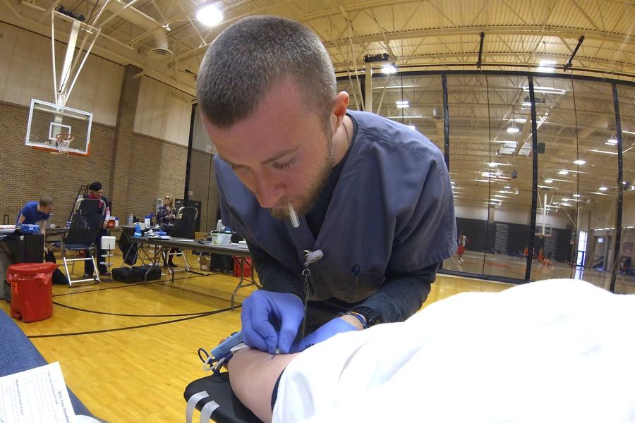 Senior Katie Johnston watches the United Blood Services technician guid the needle into her arm during the Blood Drive held in the Texas High School Tiger Center.