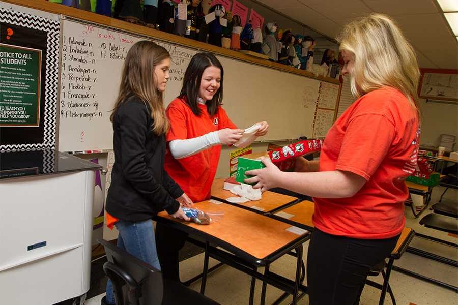 Members Katie Shupe, Sarah Stark and Libby Northam prepare gifts for the service project Operation Christmas Child