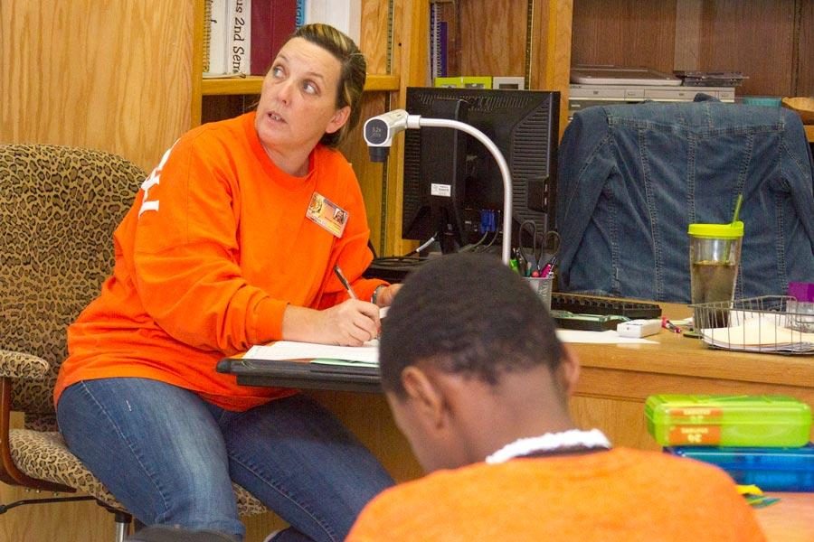 Rhonda Johnson peers works through math problems with her students at Texas High School.