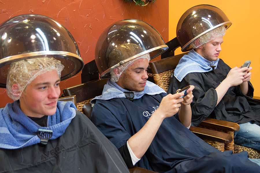 Juniors Tyler Snell, Conor Diggs and Luke Calhoun sit in hair dryer chairs waiting for bleach to process