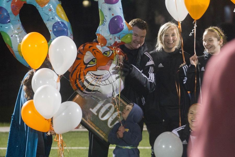 Coach Dustin Holly peaks around balloons given to him to celebrate his 100th coaching victory at Texas High School.