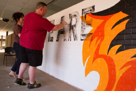 Art teachers Rebecca Hill and Tyson Feemster fill in the words of the mural. It reads "We are Tiger Strong" the mantra.