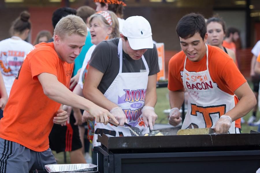 Seniors Nick Kelley, Braden Sellers and J.T. Morgan scramble eggs and fry bacon to feed the student body during the 2015 Bacon Fry at Texas High School.