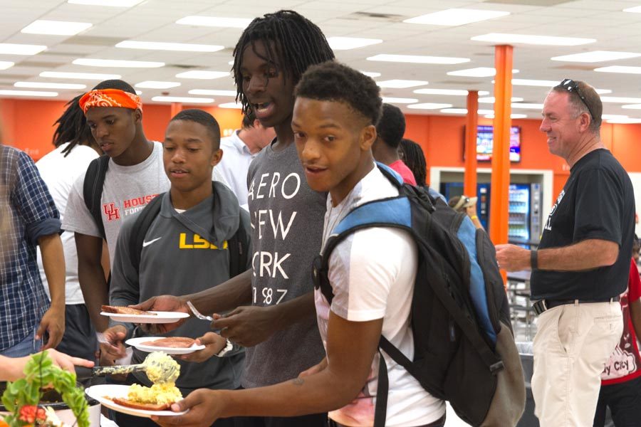 Football players enjoy a meal prepared by the cheerleaders at the annual hog supper. 