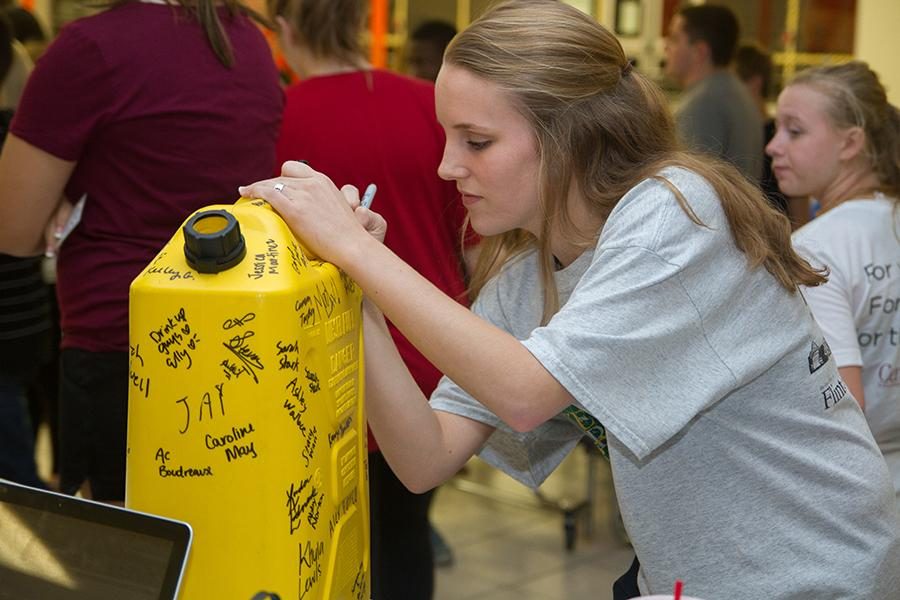 Senior Anna Graves signs thirst project jug in support of her pledge.