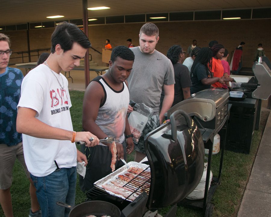 Seniors Grant Owens, Jordan Thomas and Dylan Raley cook bacon on a grill during the bacon fry. The morning before the Texas vs. Arkansas game seniors gather to prepare breakfast for the student body.