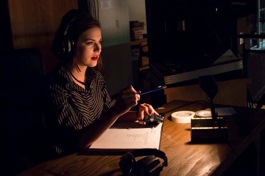 Madison Sutton dons headphones for communication with crew as she works in the technical booth. Sutton has served as stage manager in many theater productions.