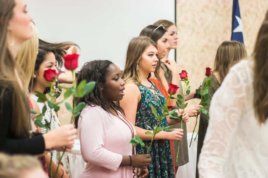 Junior members line up to present roses to their new little sisters.