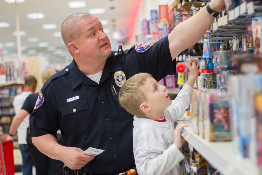 Officer Hobbs assists a child with getting a toy thats out of reach. The annual Shop with a Cop was held on Dec 6 at Target where 103 students were able to receive an early Christmas from local police and firefighters.