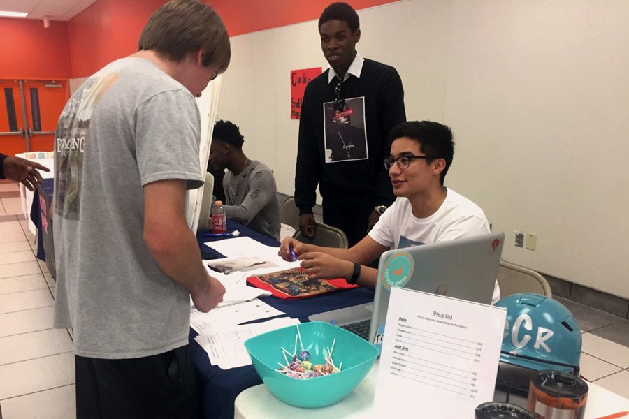 Odin Contreras and Michael Murphy talk to a student during the Entrepreneurship Showcase. DECA hosted the Showcase to promote students with businesses. Submitted photo