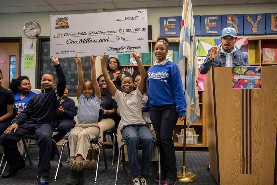 Students hold up a check for $1 million dollars from Chance the Rapper, right, who holds a press conference at Westcott Elementary School in Chicagos Chatham neighborhood on March 6, 2017. Photo by Zbigniew Bzdak