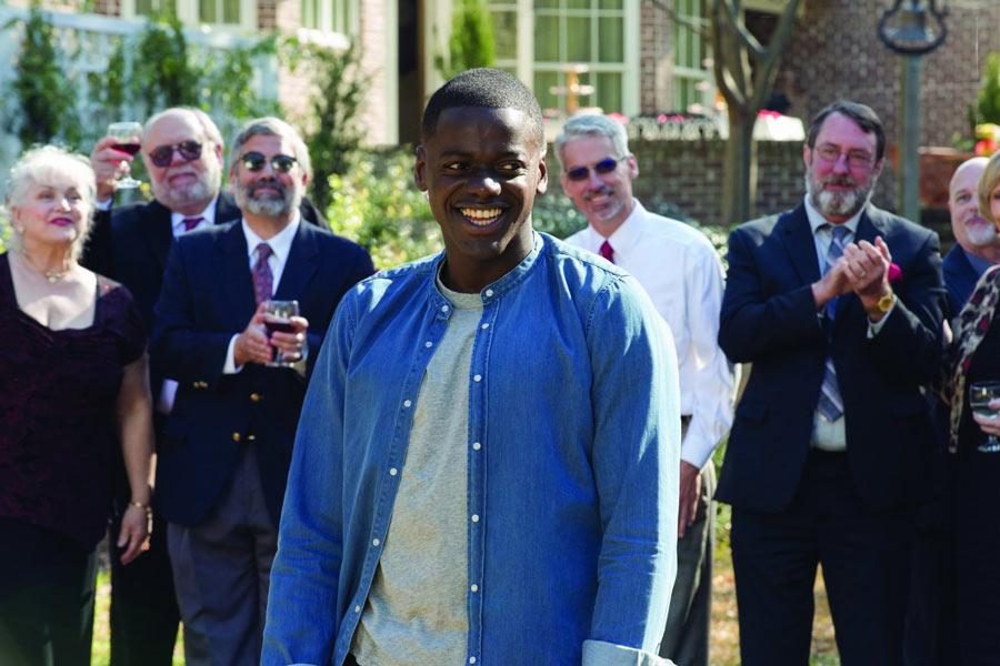 Chris, played by Daniel Kaluuya, surrounded by white dinner guests in Get Out. Photo from IMDb.
