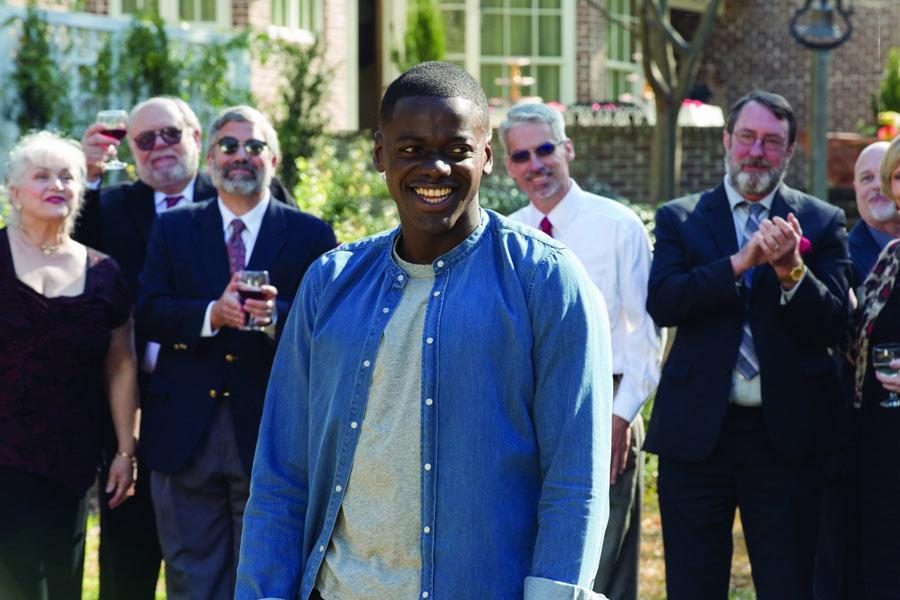 Chris%2C+played+by+Daniel+Kaluuya%2C+surrounded+by+white+dinner+guests+in+Get+Out.+Photo+from+IMDb.