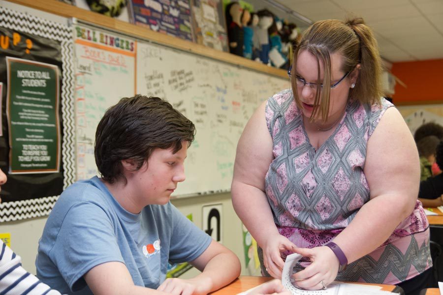 Holly Mooneyham helps a student in one of her freshman English classes. Mooneyham grew up in an abusive home and was eventually put into foster care, but she was able to overcome her past to become a successful teacher.