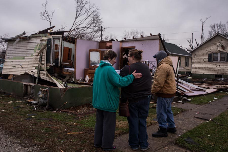 Resident Nancy Warner, center, gets a hug from Sherry Pagakis as she surveys tornado damage to her house on Wednesday, March 1, 2017 in Naplate, Ill. Neighbor Kip Frazier is on the right. Photo by Zbigniew Bzdak