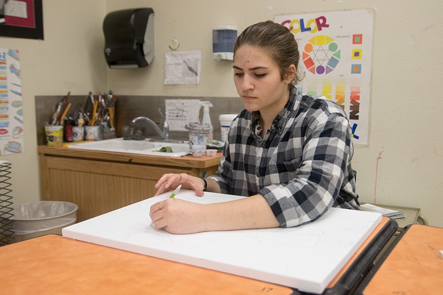 Senior Karissa Smith outlines her painting that Art Club will donate to the Texarkana Friendship Center.