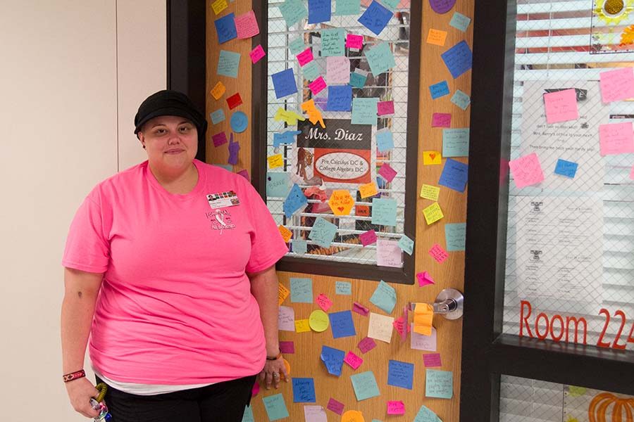 Math teacher Kathryn Diaz stands next to her door filled with notes of encouragement after coming back on campus from chemotherapy.