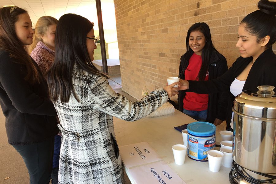 Estephanie Olvera, sells sells hot chocolate to senior Vice President of HOSA Vy Doan.