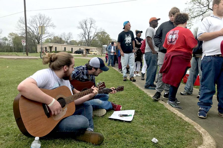 Musicians Hudson Davis and Mark Meadows sit on the grass and play worship songs. They volunteered to play music at a Christian Warriors outreach event on March 25, which was aimed to help feed the homeless. They do this once a month, and partner with other churches as well. 