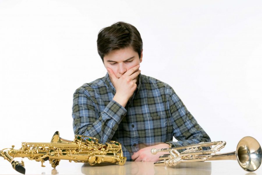 Sophomore Grey Johnson is contemplating his thoughts of two brass instruments. He has decided which instrument to start playing first. 