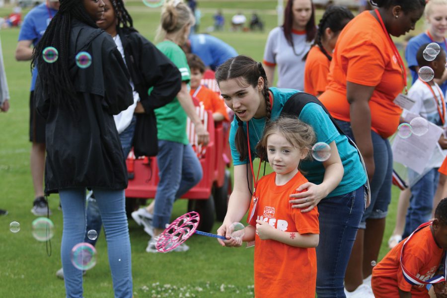 Junior Brittany Kile helps a student make bubbles. The Tiger Strong Field Day was held on May 1.