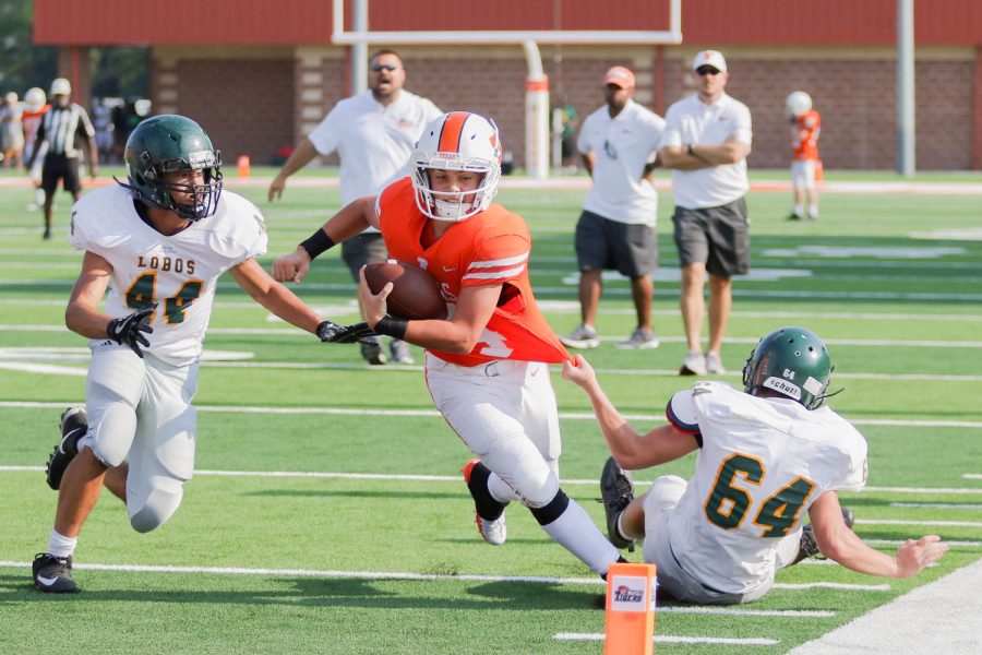 Sophomore JV quarterback Jackson Halter drags a defender towards the end zone at the JV scrimmage played before varsitys on August 24th at Tiger Stadium. 