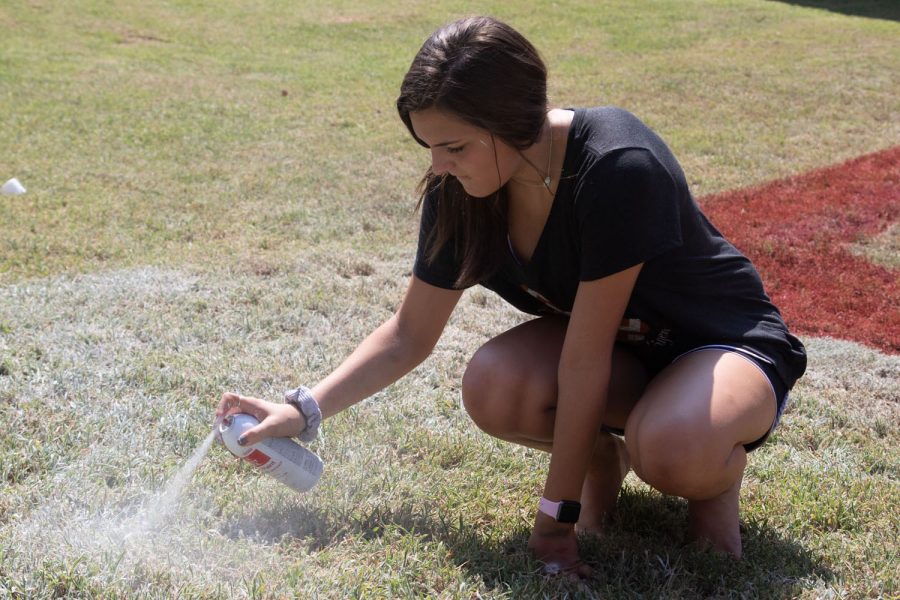 Sophomore Madisyn Givens spray paints the pit. Givens is continuing a Texas vs Arkansas tradition.