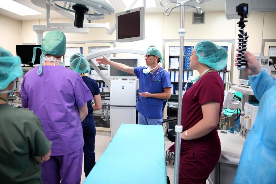 Doctors point out surgical equipment to students in an operating room.