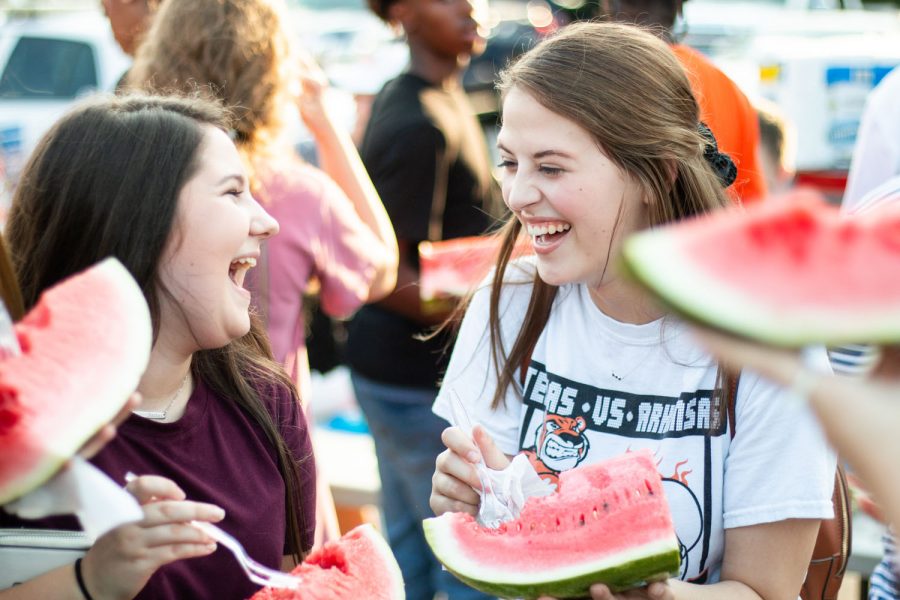 Seniors Abby Cannon and Rachel Johnson converse over watermelon at the annual back-to-school Watermelon Supper which was held in the Texas High courtyard to celebrate  the start of school.