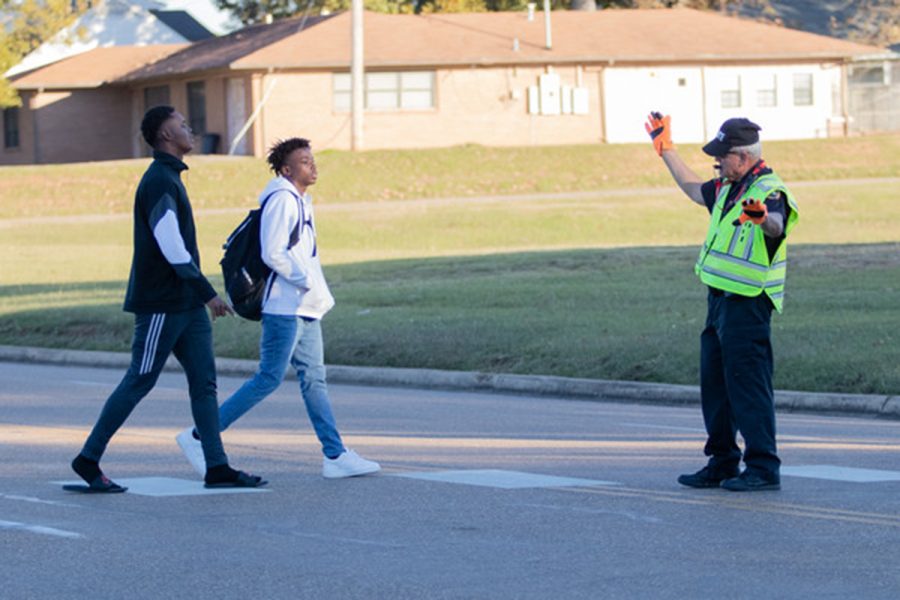 Traffic controller Keith Davis stops the flow of traffic to allow two students to cross the street. Davis has worked for Texas High for the last five years.