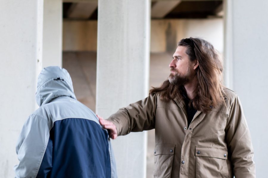 The pastor of Church Under the Bridge Cody Howard pats a church member on the back. Church Under the Bridge meets in rain or shine near the downtown area.