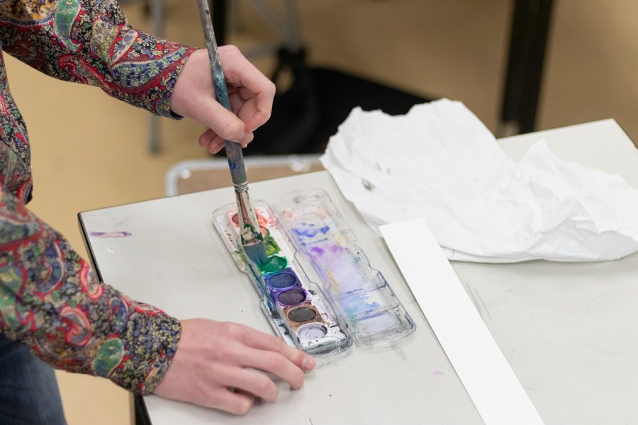 A visual arts student mixes paint while working on a competition piece. Advancing at the VASE competition next Saturday might lead to a desired scholarship.