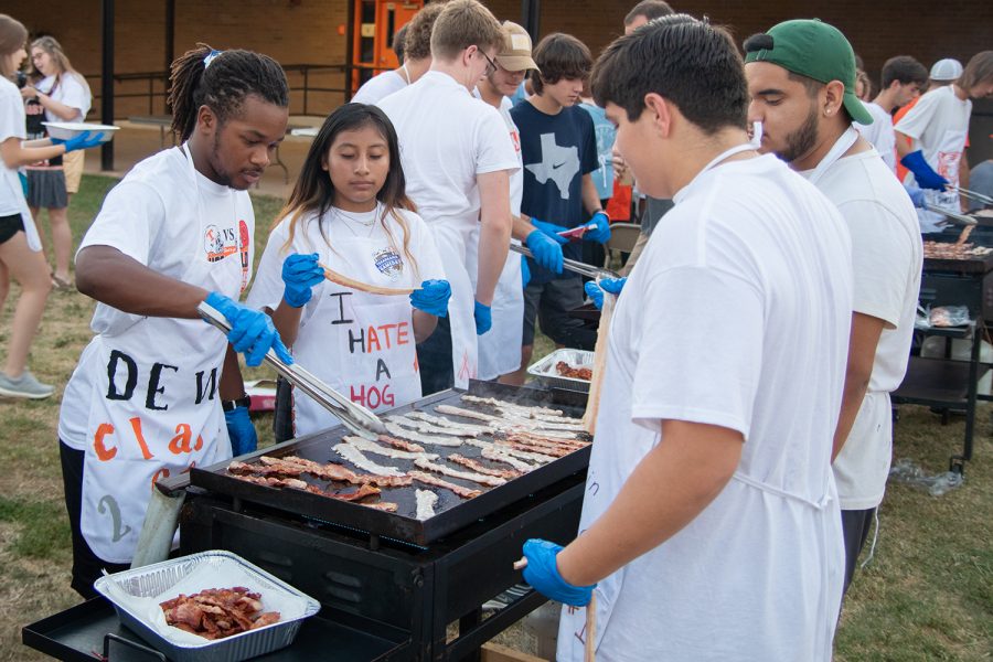 Seniors Dewoine Leeks, Rocioa Gabriel and Mathew Gass cook bacon on a propane griddle at the annual Bacon Fry the morning of the 2019 Texas vs. Arkansas football game. Seniors prepared breakfast for the rest of the student body and community.