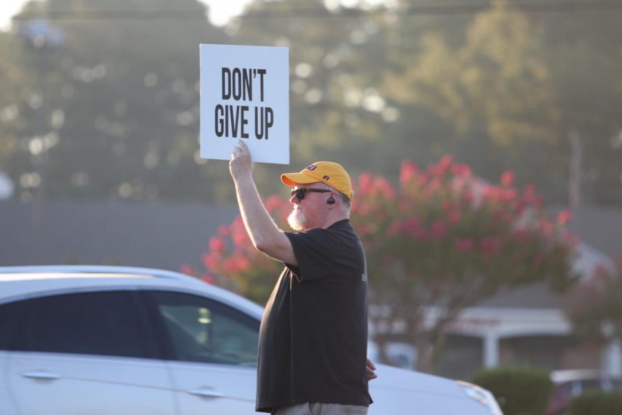 Joel+Dillahunty+holds+a+sign+to+encourage+passing+drivers.+Dillahunty+and+his+daughter+stood+near+the+road+before+school.