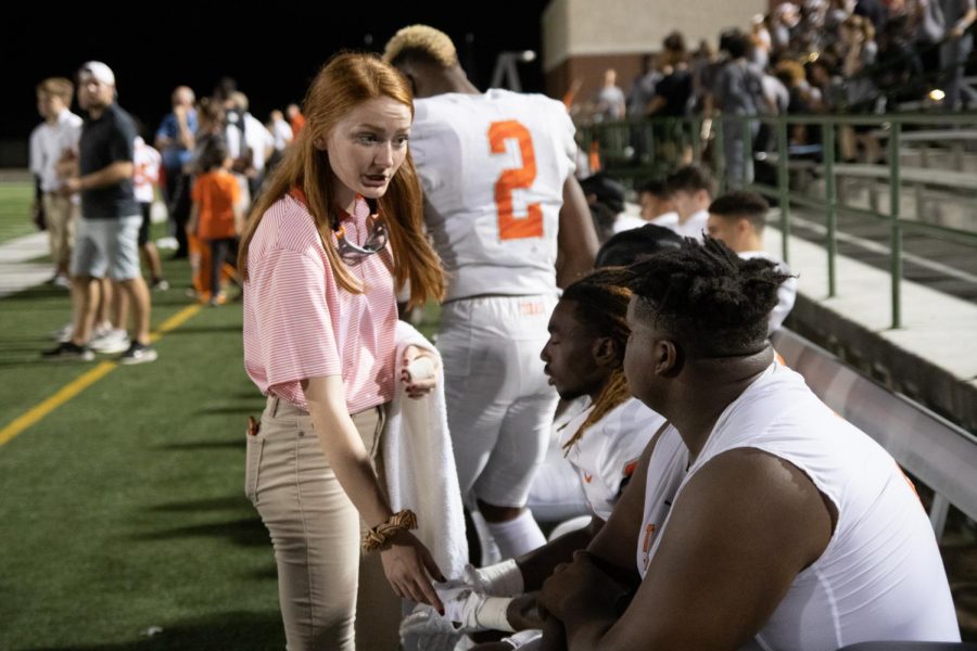 Devun Saveall checks up on a previously injured player at a football game. The student trainers work very hard at sports events to maintain the safety of players.