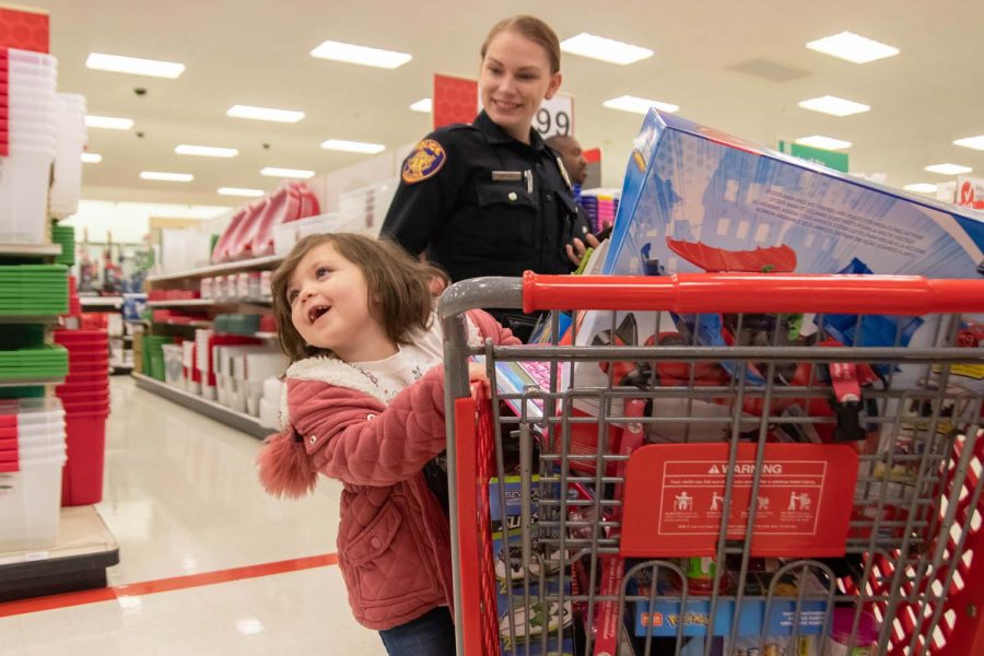 A child swings from a target shopping cart as she shops with a Texarkana police officer at the annual Shop with a Cop and Firefighter. This event allows children to interact with these local heroes in an environment that is not a direct result of an emergency situation.