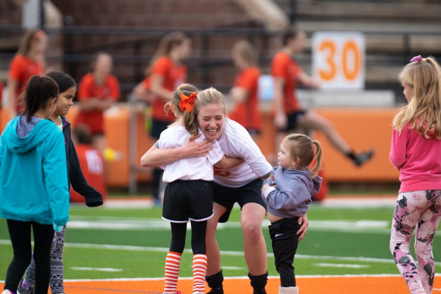 An alumni soccer player embraces a young child. Children who aspire to be soccer players were asked to come on the field after the first half to be trained by Tiger soccer players. 