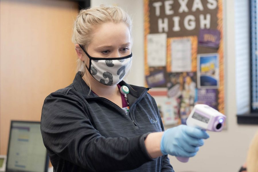 The school nurse takes a students temperature. Students are being forced to quarantine based on COVID-19 related symptoms.