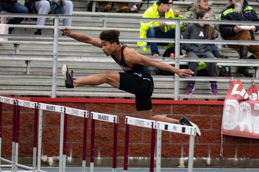  Senior Caden Miller glides over a hurdle in the 100m race. Miller competes in both hurdles and relay races.   