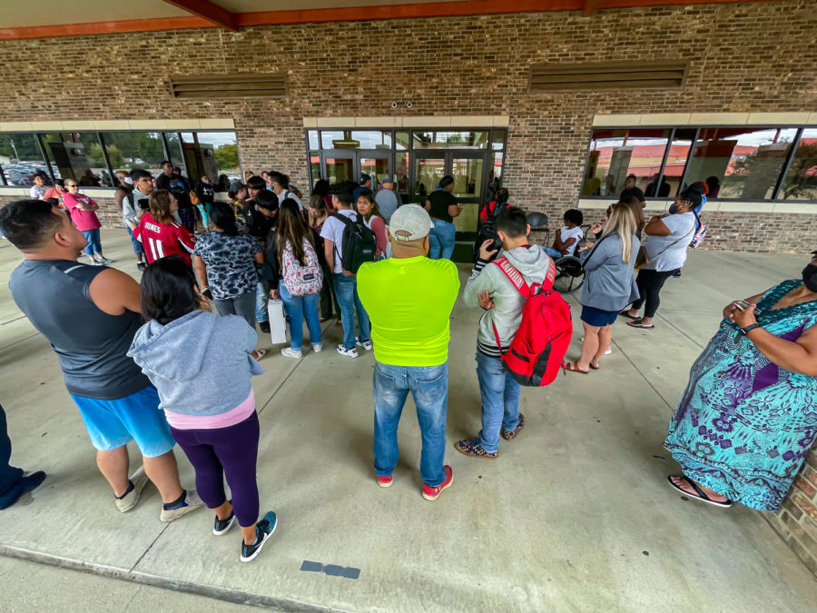 Parents wait outside the doors to the attendance office of Texas High School because of fears of retaliation after the death of a THS student yesterday. Administrators and staff ensured students left with only their parents or guardians while police provided security around campus.