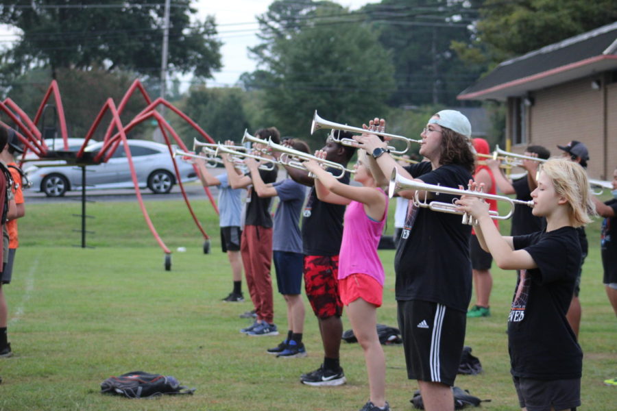 The trumpet section stands in a line as they rehearse this years marching performance, The Web.