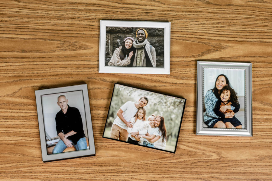 A variety of family photos lay on a desk. The definition of a family is becoming more and more diverse in Western society.