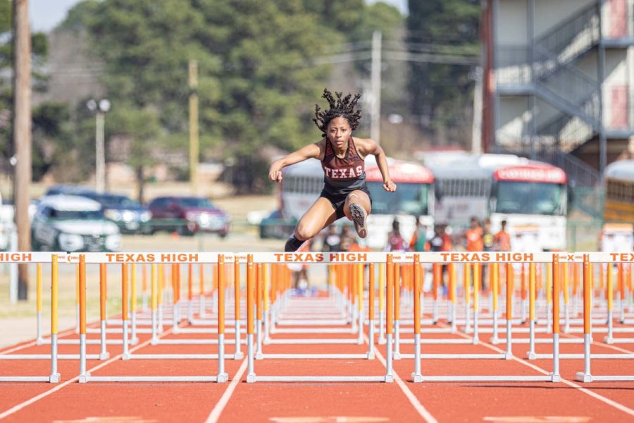 Gliding through the air, senior Lexie Edwards perfectly places herself over the hurdle to help her take a lead. The lady tigers placed second in the Watty Myers track meet on March 4, 2022. 