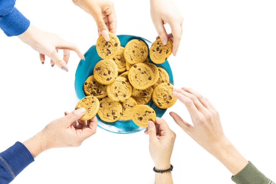 Hands grab at a plate of cookies. Senior Aislyn Echols investigated the legitimacy of the placebo effect through a taste test.