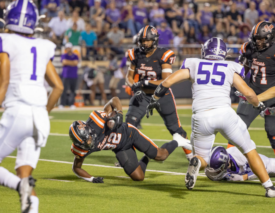 Wide receiver Tradarian Ball falls after avoiding a tackle from opposing players during the Texas versus Hallsville district game. The Tigers Defeated the Bobcats 56-31 on September 23, 2022.