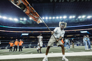 Cheer Escort Captain Daniel Lee waves a Texas Tigers flag in front of the crowd. The cheer escorts traveled with the cheer team and ran flags at the AT&T Stadium.